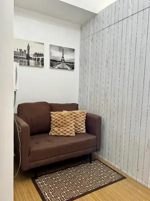 a brown couch in a room with two pictures on the wall at Taguig City Grace Residences with small balcony in Manila