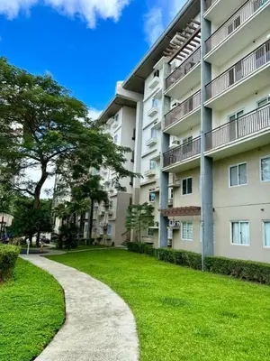an apartment building with a grassy yard next to a sidewalk at Amaia Steps Nuvali fully furnished unit with swimming pool view near Carmelray Pitland in Calamba