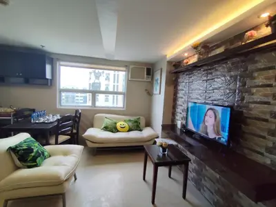 a living room with a tv on a brick wall at Gilmore Tower Suites By SMS Hospitality in Quezon City