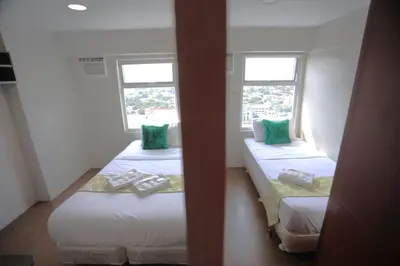 two beds in a room with two windows at Gilmore Tower Suites By SMS Hospitality in Quezon City