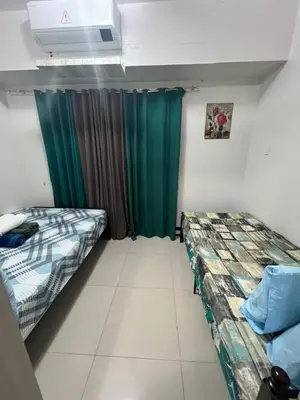 two beds in a room with green curtains at Sea Residences at Jireh in Pasay