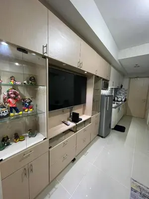 a large kitchen with a large television and cabinets at Sea Residences at Jireh in Pasay
