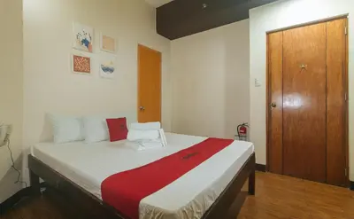 a bedroom with a large bed with a wooden door at RedDoorz near EDSA Camp Crame in Manila