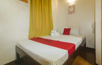 a small bedroom with a white bed with a red blanket at RedDoorz near EDSA Camp Crame in Manila