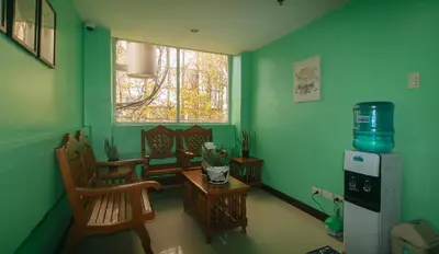 a green room with chairs and a table and a window at RedDoorz near EDSA Camp Crame in Manila