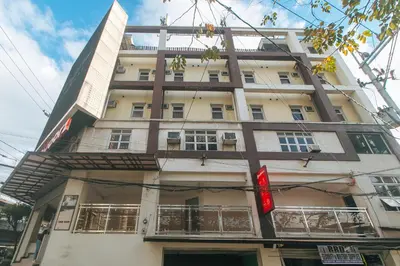 a tall white building with a red sign on it at RedDoorz near EDSA Camp Crame in Manila