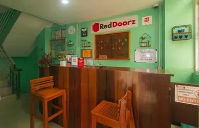 a red door restaurant with a bar and two chairs at RedDoorz near EDSA Camp Crame in Manila