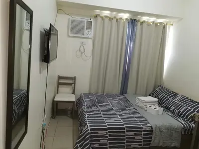 a small bedroom with a bed and a chair at Mack's Awesome Place 24 with Netflix and FastUnliwifi in Manila