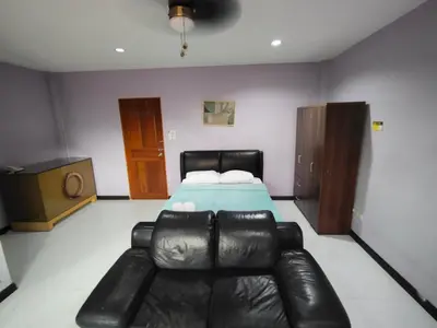a bedroom with a bed and a leather couch at La Belladoza near NAIA T1 Airport in Manila