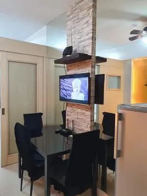 a dining room with a table and a tv on a brick wall at Vangie's Place at SEA RESIDENCES in Manila