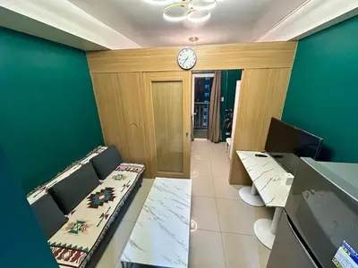 a room with two tables and a clock on the wall at Kathys Crib at Shell Residences in Manila