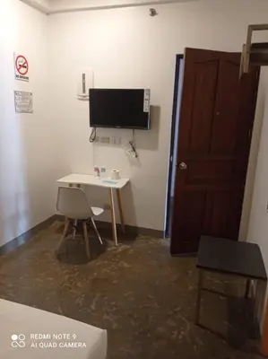 a room with a desk and a computer monitor on a wall at 8 Zhensen Inn in Bacoor