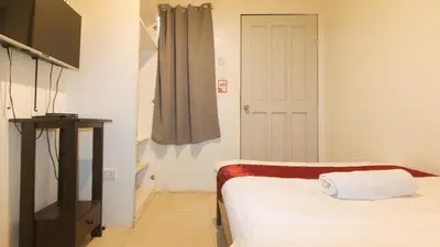 a bedroom with a bed and a door with a curtain at Nearest Hostel Pasay City by RedDoorz in Manila
