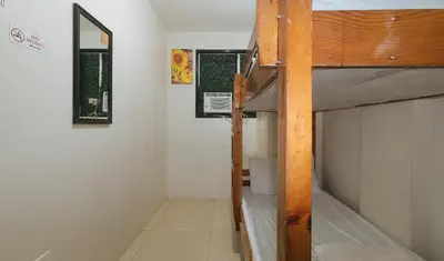a small room with a bunk bed and two windows at Nearest Hostel Pasay City by RedDoorz in Manila