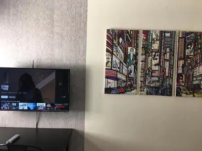a flat screen tv sitting on a wall next to a painting at Ronz Deca Hills in Manila