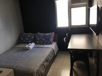 a small bedroom with a bed and a table at Ronz Deca Hills in Manila