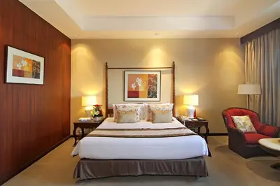 a hotel room with a bed and a red chair at The Manila Hotel in Manila