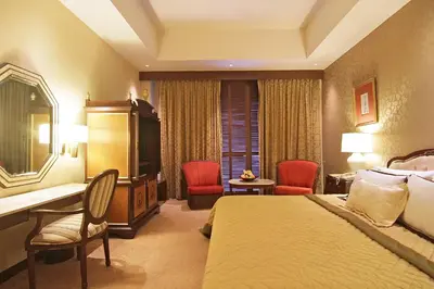 a hotel room with a bed and a desk and chairs at The Manila Hotel in Manila