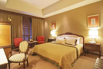 a hotel room with a bed and a desk and chairs at The Manila Hotel in Manila