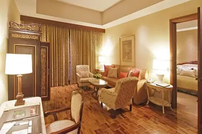 a living room with a couch and chairs and a bed at The Manila Hotel in Manila