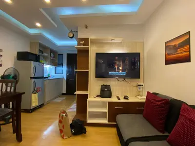 a living room with a couch and a tv on a wall at MidKnight Sky Unit for Rent in Anabu Primero