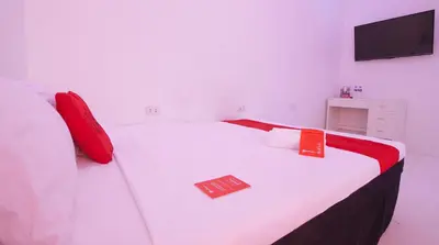 a white bed with red pillows and a sign on it at RedDoorz @ Jolly Orange Paranaque in Manila