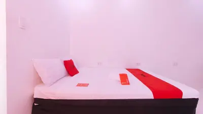 a white bed with red and white pillows on it at RedDoorz @ Jolly Orange Paranaque in Manila