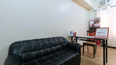 a living room with a couch and a table with a laptop at RedDoorz @ Jolly Orange Paranaque in Manila