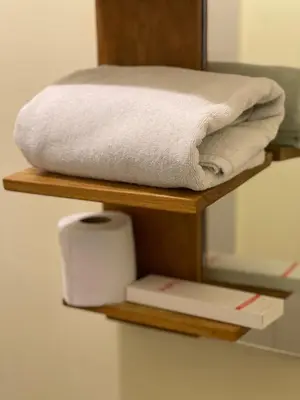 a wooden shelf with towels and a toilet paper on it at airobedz MANILA - A Value Hotel in Manila