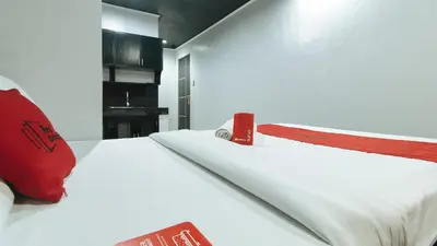 a bedroom with a white bed with a red pillow at RedDoorz @ Good 101 Quiricada Manila in Manila