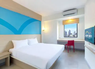 a bedroom with a white bed and a red chair at Hop Inn Ortigas Center Manila in Manila