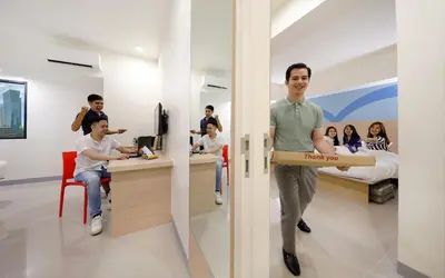 a man walking through a room with a pizza box at Hop Inn Ortigas Center Manila in Manila
