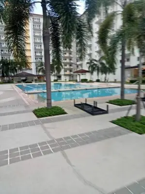 a swimming pool with palm trees in a city at Field Residences in Manila