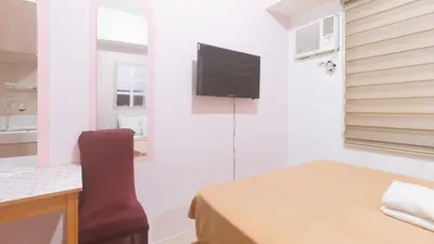 a room with a bed and a television on a wall at Eimys Place at Urban Deca Mandaluyong by RedDoorz in Manila