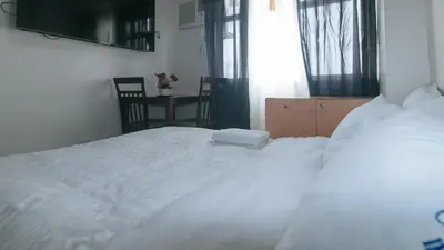 a white bed in a room with a window at Eimys Place at Urban Deca Mandaluyong by RedDoorz in Manila