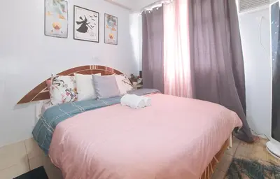 a bedroom with a large bed with a pink blanket at Eimys Place at Urban Deca Mandaluyong by RedDoorz in Manila