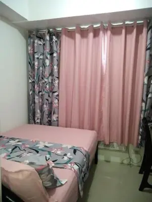 a bedroom with a bed and a window with pink curtains at MSH property Sea Residences MOA Pasay City by Queennie in Manila
