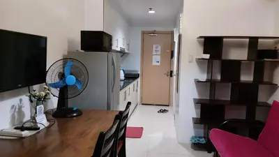 a room with a table with a fan and a kitchen at MSH property Sea Residences MOA Pasay City by Queennie in Manila