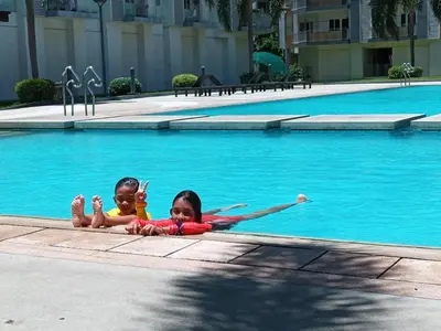 two children laying in the water in a swimming pool at Lovely Condo 2-BR w/balcony in SM-Sucat, Paranaque in Manila