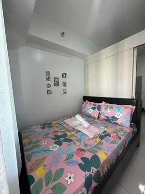 a bedroom with a bed with a floral bedspread and pillows at Sea Residences MOA Complex - Ruffa's Condotel in Manila