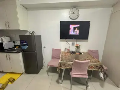 a kitchen with a table and chairs and a clock on the wall at Sea Residences MOA Complex - Ruffa's Condotel in Manila