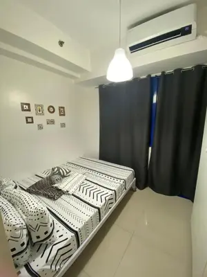 a bedroom with a bed and a black curtain at Sea Residences MOA Complex - Ruffa's Condotel in Manila