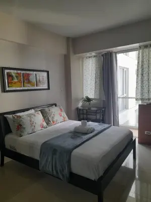 a bedroom with a bed and a large window at One Palm Tree Villas-Kenzie Place Terminal 3 Airport in Manila