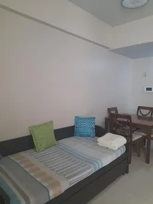 a bed in a room with a table and chairs at One Palm Tree Villas-Kenzie Place Terminal 3 Airport in Manila