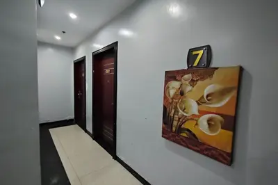 a hallway with a clock on a wall next to a door at Manila Crown Palace Hotel in Manila