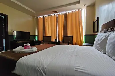 a bedroom with a large white bed and a living room at Manila Crown Palace Hotel in Manila