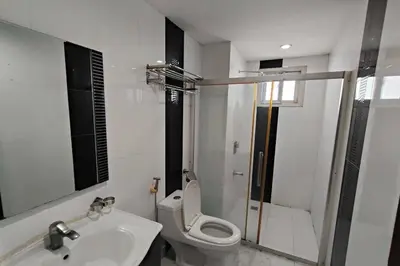 a white bathroom with a toilet and a sink at Manila Crown Palace Hotel in Manila