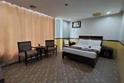 a bedroom with a bed and two chairs and a table at Manila Crown Palace Hotel in Manila