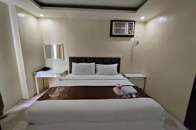 a bedroom with a large bed and two night stands at Manila Crown Palace Hotel in Manila
