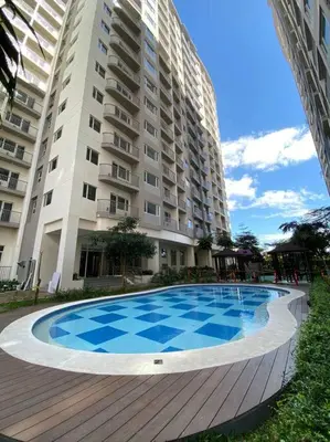 a swimming pool in front of a large building at A Cozy 1 Bedroom Unit with a Parking at Tower 2 South Residences SM Southmall in Manila